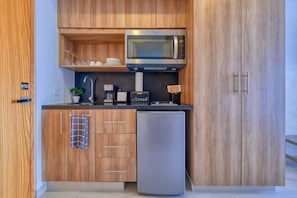 Una cocina moderna con armarios de madera, un refrigerador de acero inoxidable, un microondas y una cafetera.