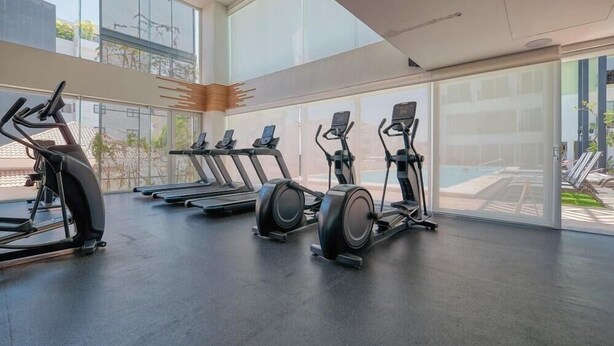 Ein Fitnessstudio mit Laufbändern, Crosstrainern und einem großen Panoramafenster.