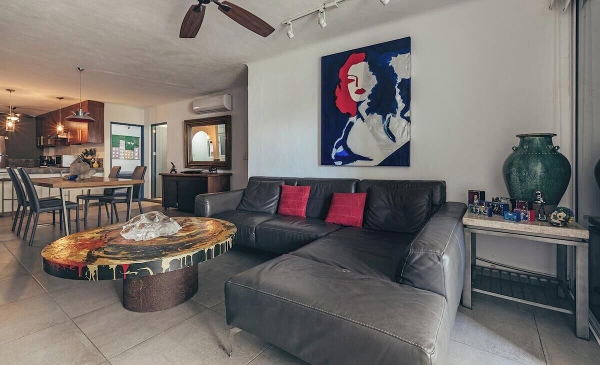 A modern living room with a sectional sofa, a coffee table, and a painting on the wall.