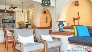 A modern lobby with a reception desk, two grey armchairs, a sofa, and a decorative horse statue. - Ocean View 1Br Condo-balcony-beach-pool - 606 (Puerto Vallarta)