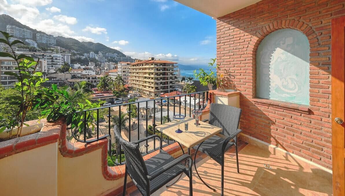 Un balcón con mesa y sillas, con vistas a la ciudad y al mar.