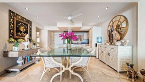 A spacious dining area with a glass table, white chairs, and a decorative centerpiece. - Ocean View 2Br Condo-balcony-beach-pool - 712 (Puerto Vallarta)