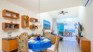 Comedor con mantel azul, sillas de madera y estantes con objetos decorativos.
