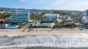 Un hotel costero con varias edificaciones, una playa y una zona de piscina.