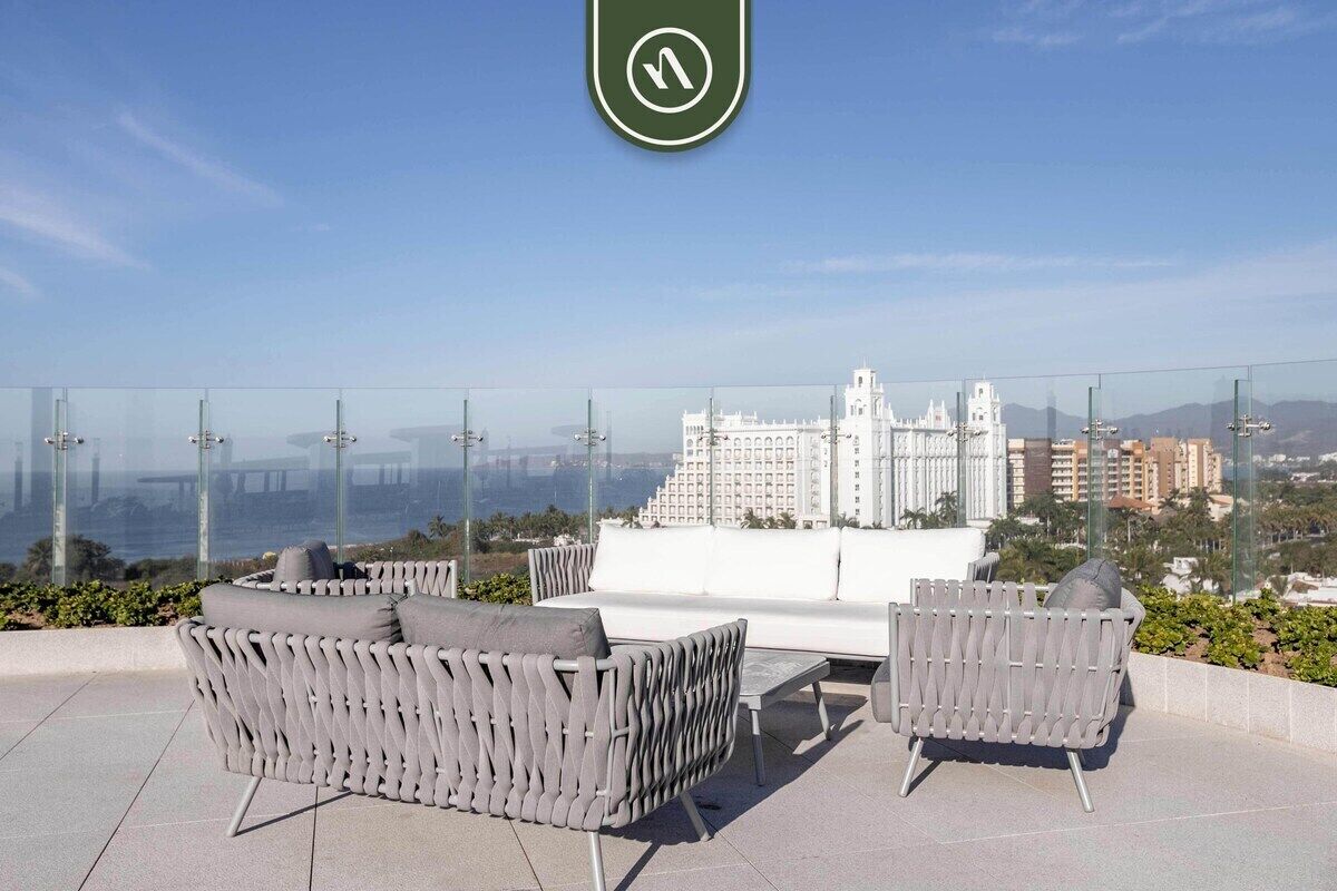 Terraço no telhado com mobiliário externo e vista para a cidade.