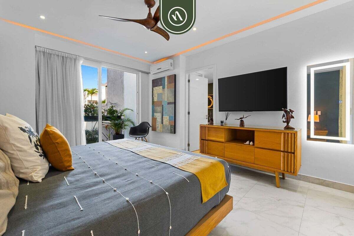 Un dormitorio moderno con una cama grande, un mueble de televisión de madera y un ventanal amplio.