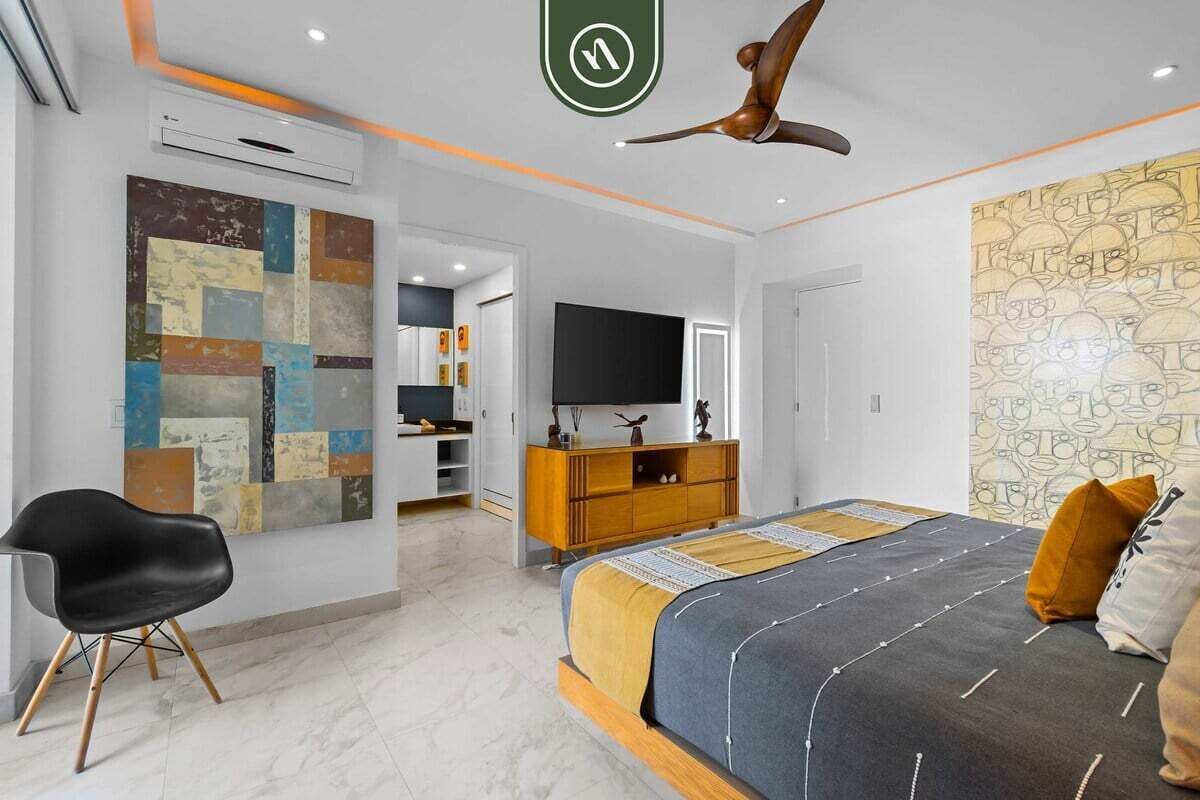 Una camera da letto moderna con un letto, una televisione, una ventola a soffitto e una parete con un motivo geometrico.