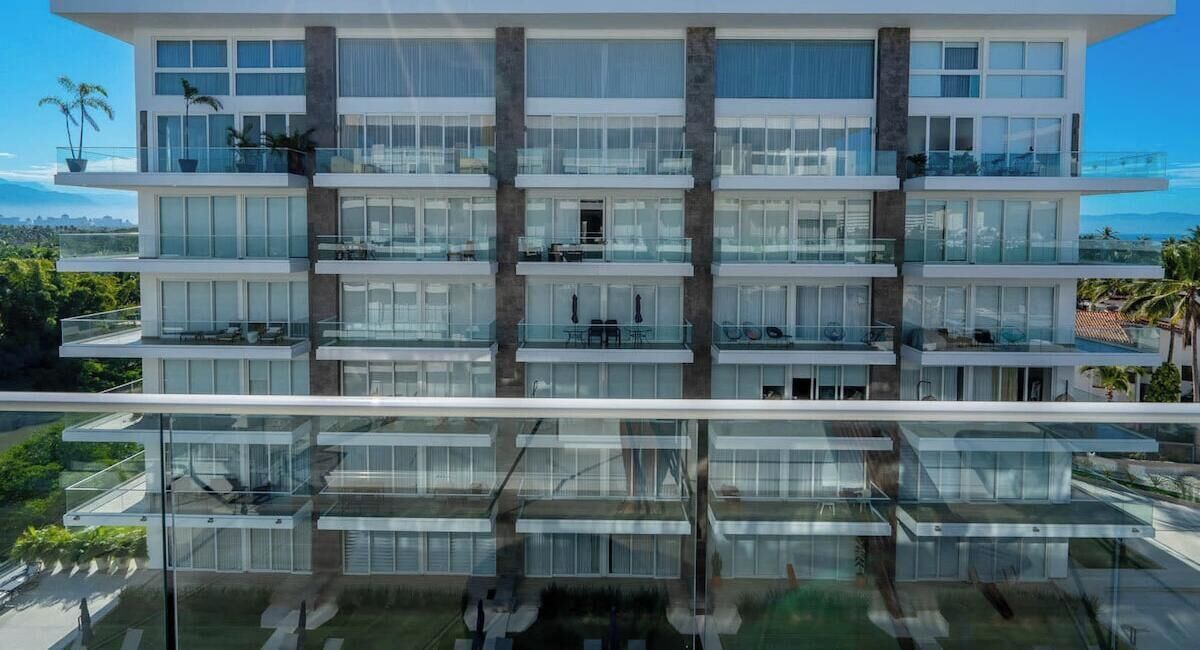 Un edificio de varios pisos con balcones, ventanas amplias y fachada de vidrio reflectante.