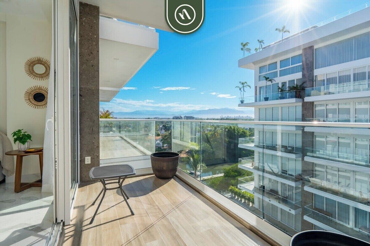 A balcony with a view of a modern building, a potted plant, and a small table.