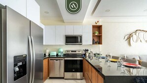 A modern kitchen with stainless steel appliances, a central island, and a dining area with a sofa.