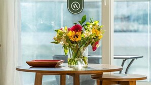 A round wooden table with a clear glass vase containing a bouquet of flowers.