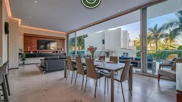 Una sala de estar moderna con comedor, ventanas amplias y un televisor de pantalla plana.