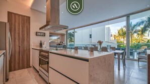 A modern kitchen with a large island, built-in oven, and a view of the outdoor seating area.
