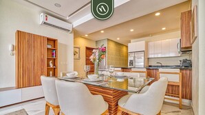 Una cocina moderna con armarios blancos, una isla de madera y una mesa de comedor de vidrio con cuatro sillas.