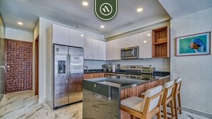 Una cocina moderna con una isla central, electrodomésticos de acero inoxidable y taburetes de madera.