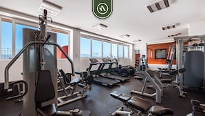 A gym with various exercise equipment, large windows, and a view of the outdoors.