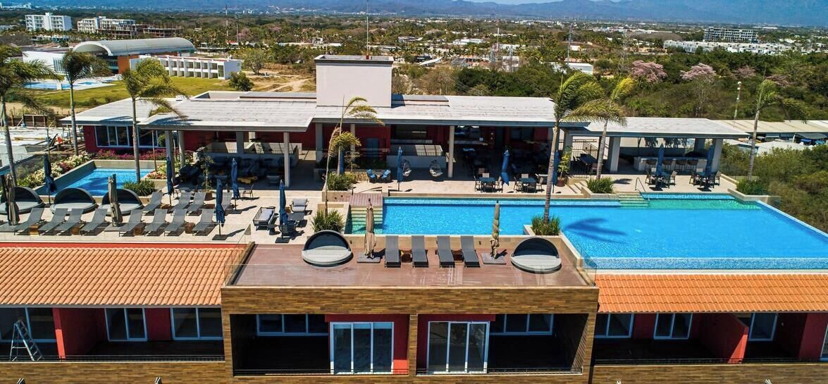 Un hotel con piscina sul tetto, poltrone relax e vista sul paesaggio circostante.
