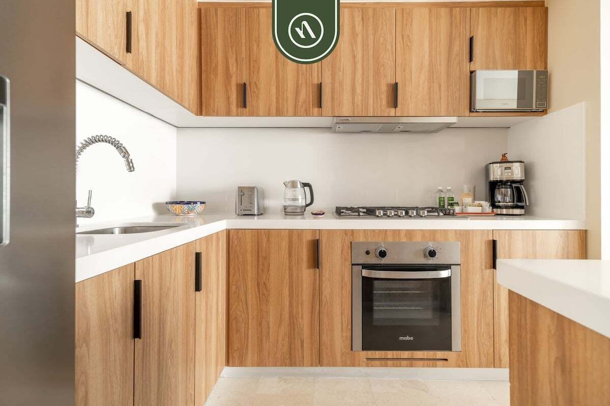 A modern kitchen with wooden cabinets, a built-in oven, a microwave, and a coffee maker.