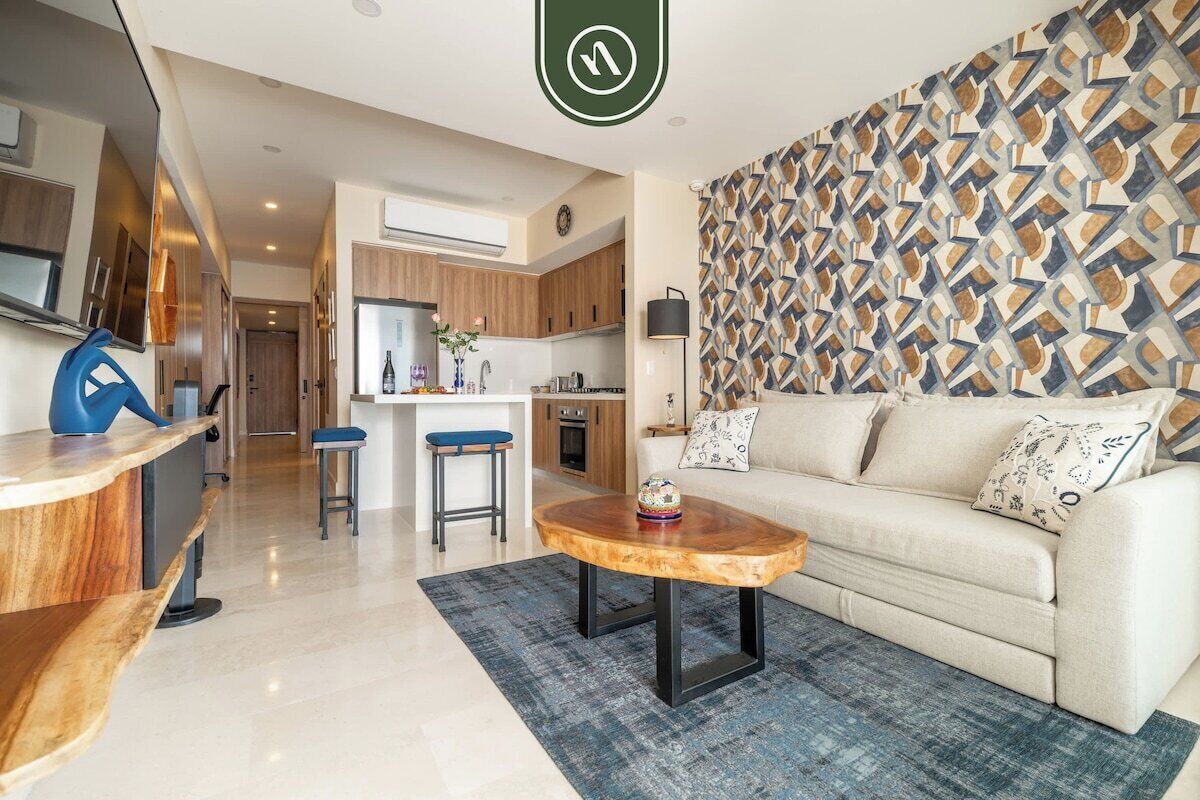 A modern living room with a sofa, coffee table, and kitchen in the background.
