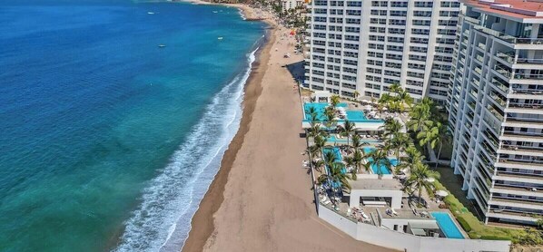 A beachfront hotel with a pool, beach access, and high-rise buildings.