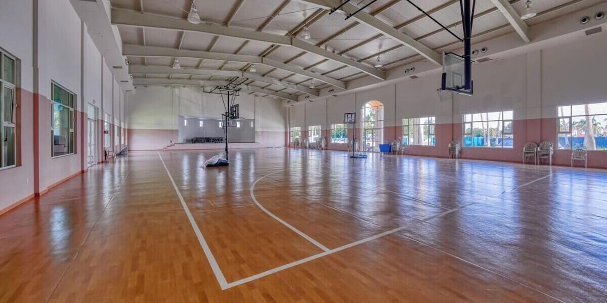 A spacious indoor basketball court with a high ceiling and large windows.