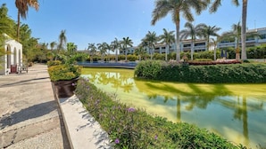 A resort with a pool, palm trees, and a building with multiple floors. - Amazing 2BR Condo in Nuevo Vallarta - Pool - King (Nuevo Nayarit)