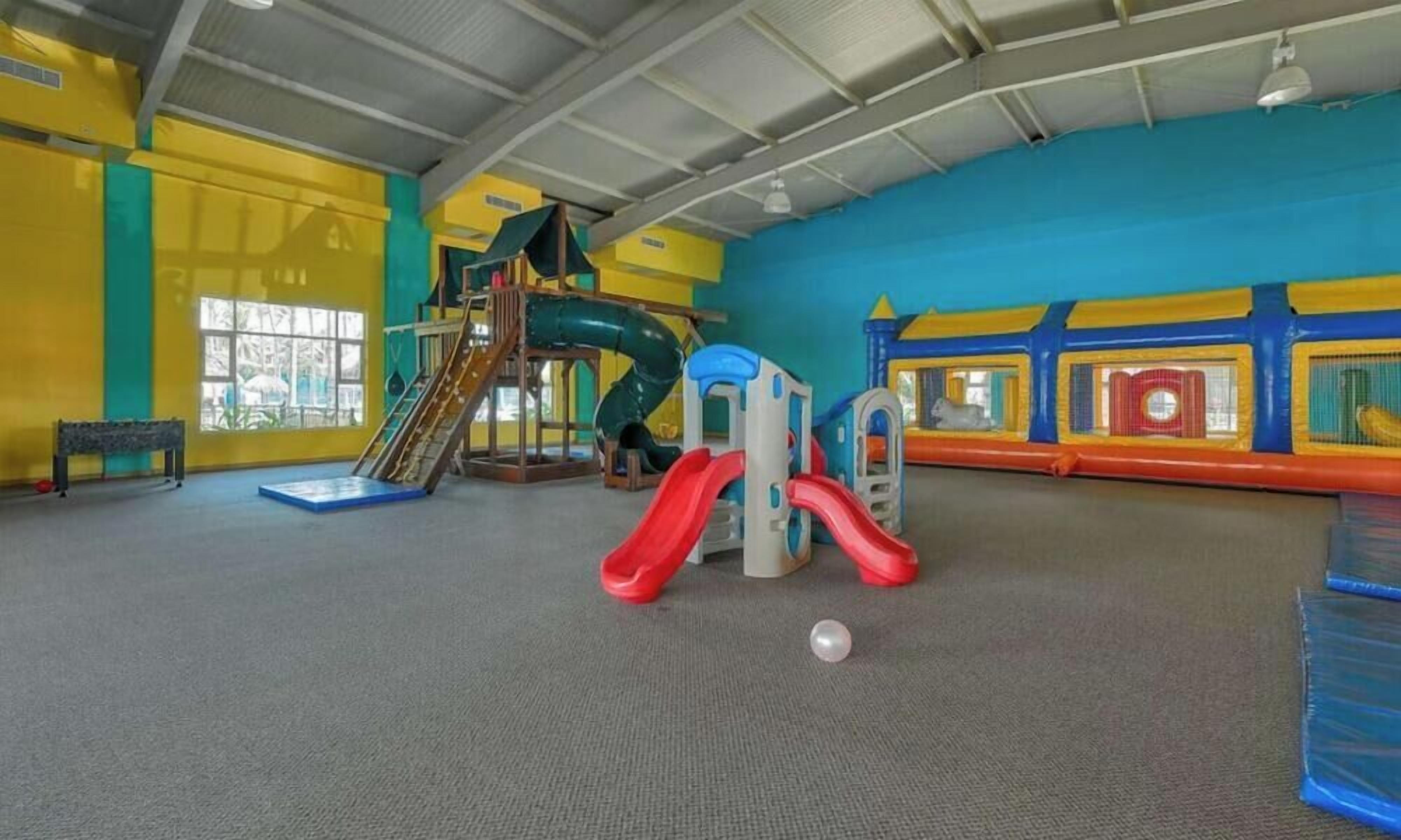 Ein Spielbereich mit Rutsche, Klettergerüst und gepolsterten Spielzonen.