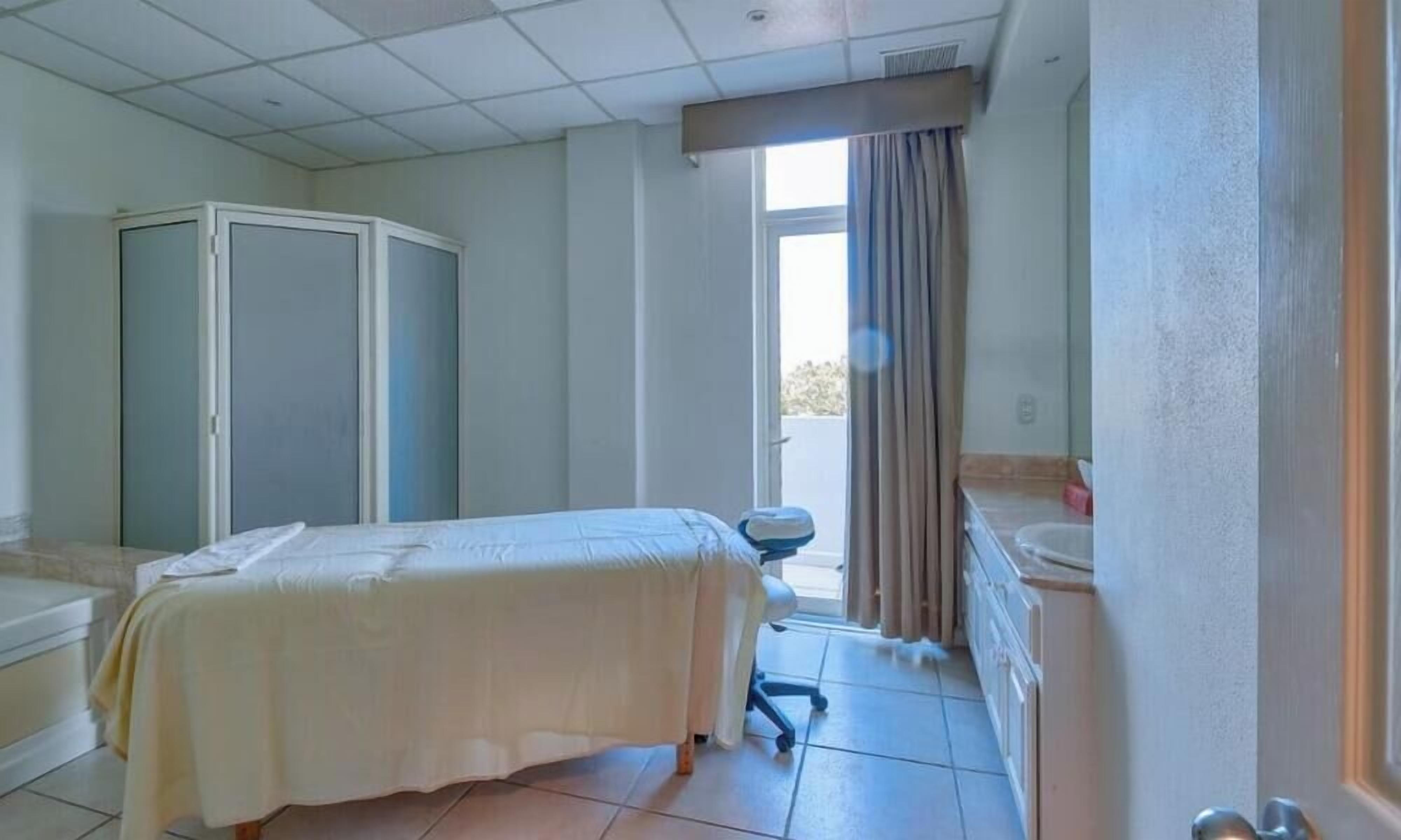 A hotel room with a bed, a wardrobe, a bathroom with a bathtub, and a view of the outside.