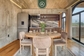 A modern kitchen with a marble backsplash, a dining area with a round table and chairs, and a large window offering a view.