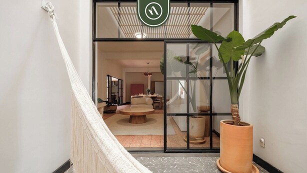 A hallway with a hammock, a large potted plant, and a sliding glass door leading to a room with a round table and chairs. - Centric 3BR Condo in Downtown in Oaxaca (Oaxaca)