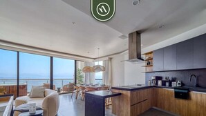 A modern kitchen with a central island, wooden cabinets, and a view of the ocean. - Luxury Oceanfront 3 BR Condo With Balcony (La Cruz de Huanacaxtle)
