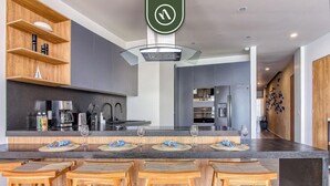 A modern kitchen with a central island, bar stools, and built-in appliances. - Luxury Oceanfront 3 BR Condo With Balcony (La Cruz de Huanacaxtle)
