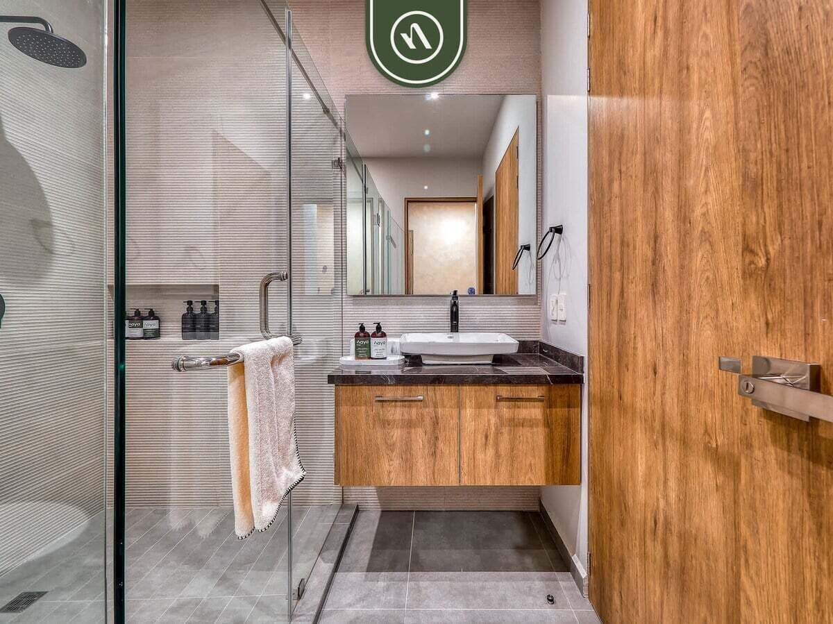 A modern bathroom with a glass shower enclosure, a wooden vanity with a sink, and a towel rack.