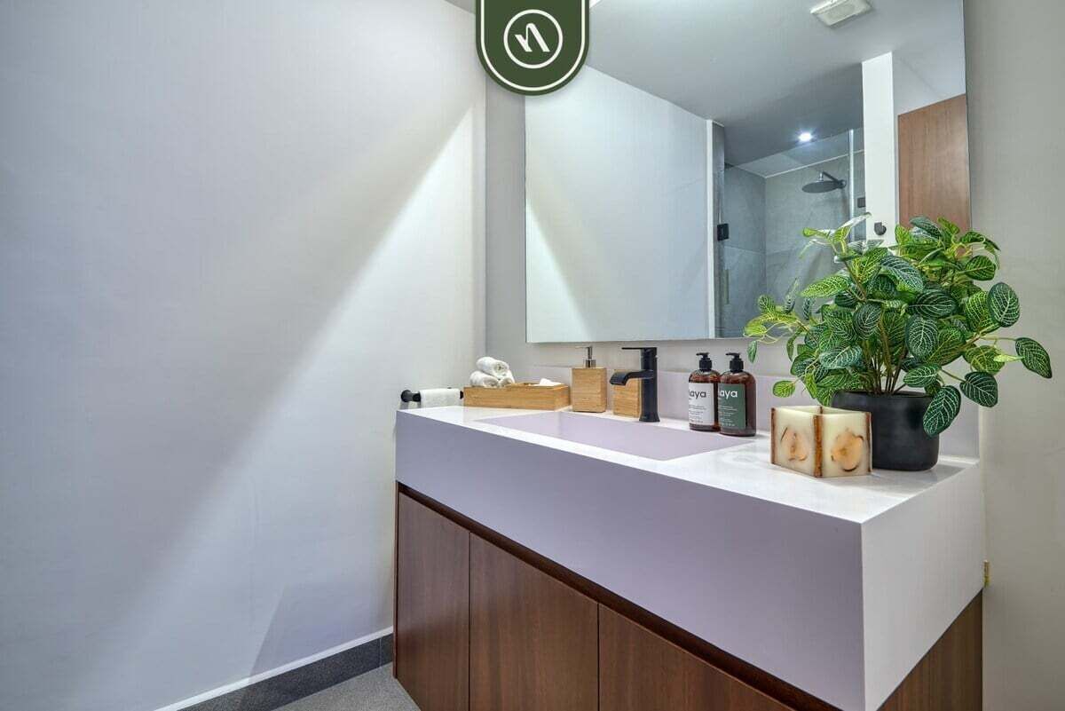 Un baño moderno con un tocador blanco, un espejo grande y una planta en maceta.
