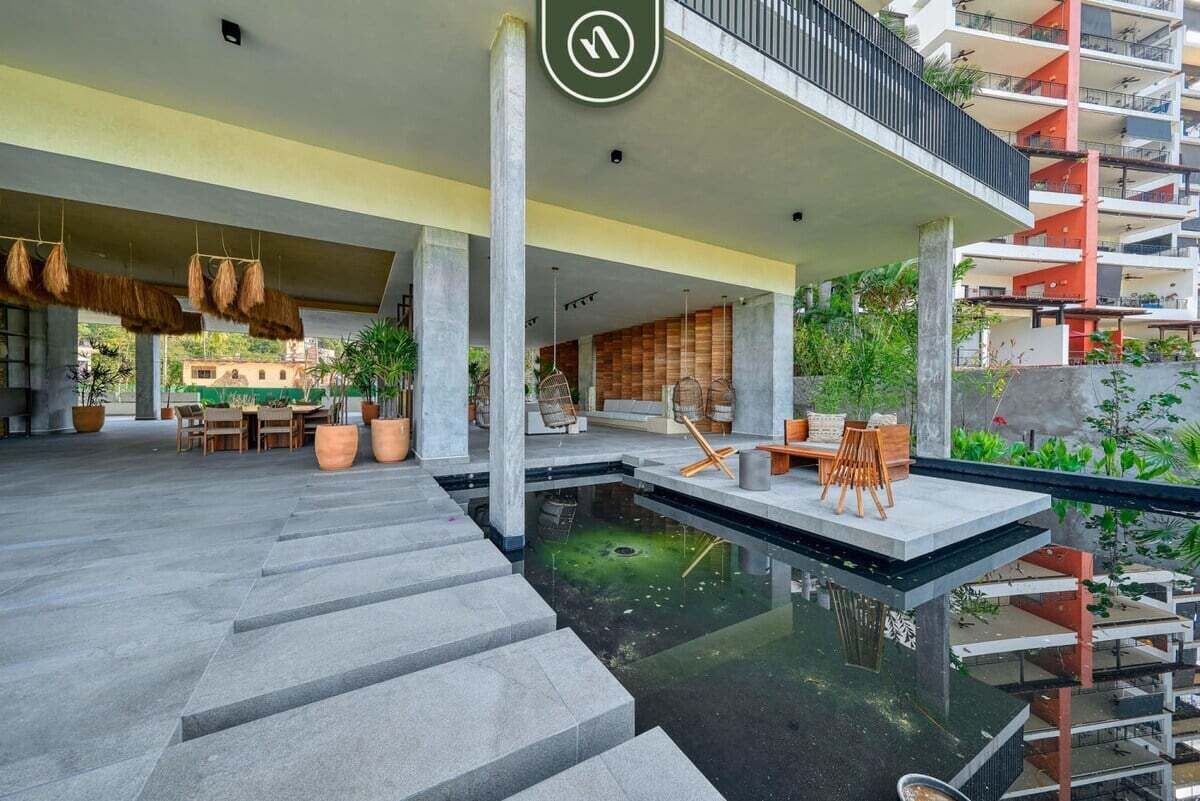 Een modern gebouw met een centrale binnenplaats, terras en een kleine waterpartij.