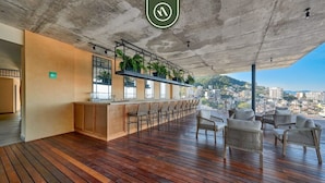Un bar panoramico con pavimento in legno, posti a sedere e un bancone bar con piante.