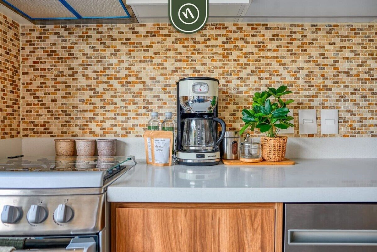 Une cuisine avec un mur recouvert de briques, une machine à café et une cuisinière.