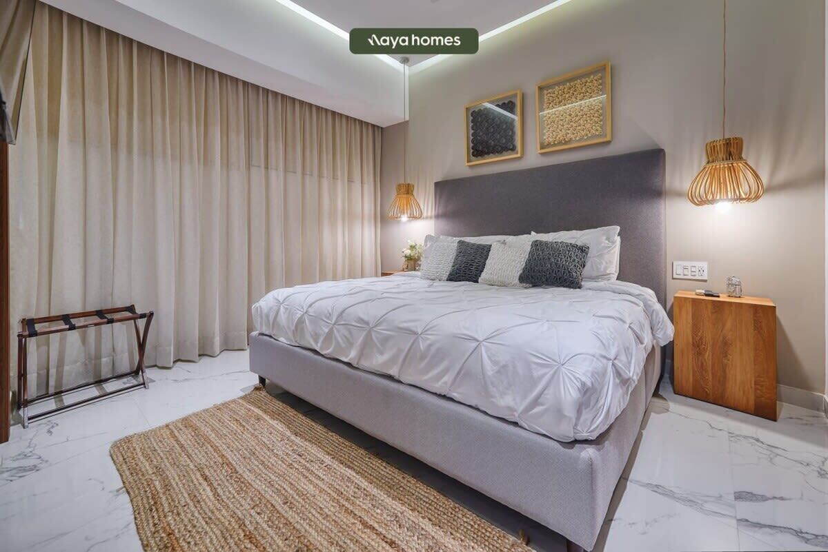 Un dormitorio moderno con una cama grande, una mesita de noche de madera y una lámpara de pared.