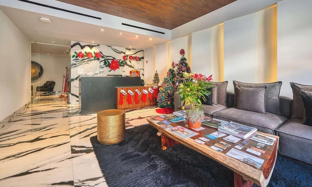 A modern hotel lobby with a reception desk, a sofa, a coffee table with magazines, and a decorative Christmas tree.