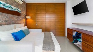 Ein modernes Schlafzimmer mit Ziegelwand, Holzschrank, Flachbildfernseher und einer Holzkabine mit Schublade.