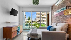 Ein modernes Hotelzimmer mit einem Bett, einem Sofa, einem Holzschrank, einem Flachbildfernseher und einem großen Fenster mit Blick auf die Stadt.