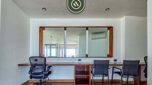 Un salón de conferencias con una larga mesa, cuatro sillas, un escritorio de madera y un amplio ventanal.
