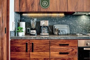 Una cucina con mobili in legno, un frullatore, una macchina da caffè, un tostapane e un fornello.