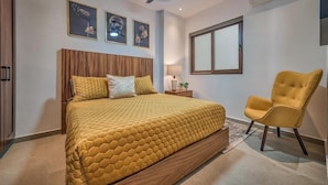 Un dormitorio con una cama grande, una mesita de noche, una silla y una ventana.