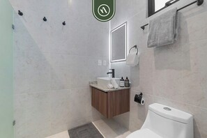 Un baño moderno con inodoro, lavabo y espejo.