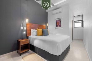 Un dormitorio moderno con cama, mesita de noche y lámpara colgante.