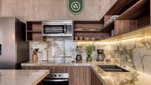 Une cuisine moderne dotée d’un four à micro-ondes, d’un four et d’un évier encastrés, de meubles en bois et de plans de travail en marbre.