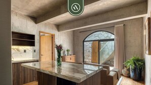 Une cuisine moderne dotée d’un plan de travail en marbre, de meubles en bois, d’un four encastré et d’une grande fenêtre offrant une vue dégagée.