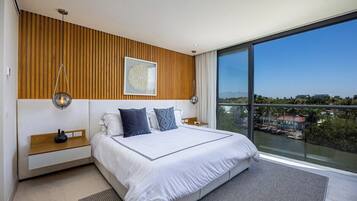 Un dormitorio moderno con una cama grande, pared de paneles de madera y vistas a un cuerpo de agua.