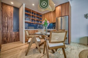 A modern kitchen with wooden cabinetry, a built-in wine rack, and a stainless steel refrigerator.
